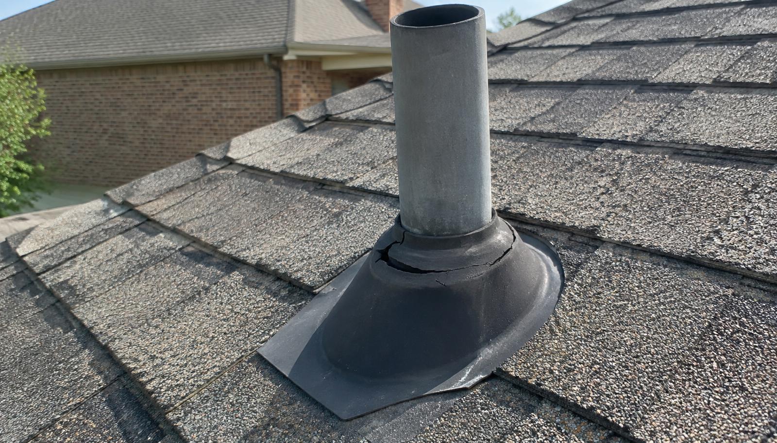 Plumbing vent pipe with a cracked rubber boot on an architectural shingle roof of a North Texas brick home